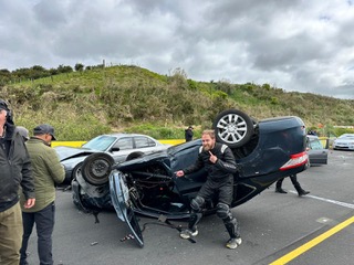 Tim Cody on set beside a flipped stunt car